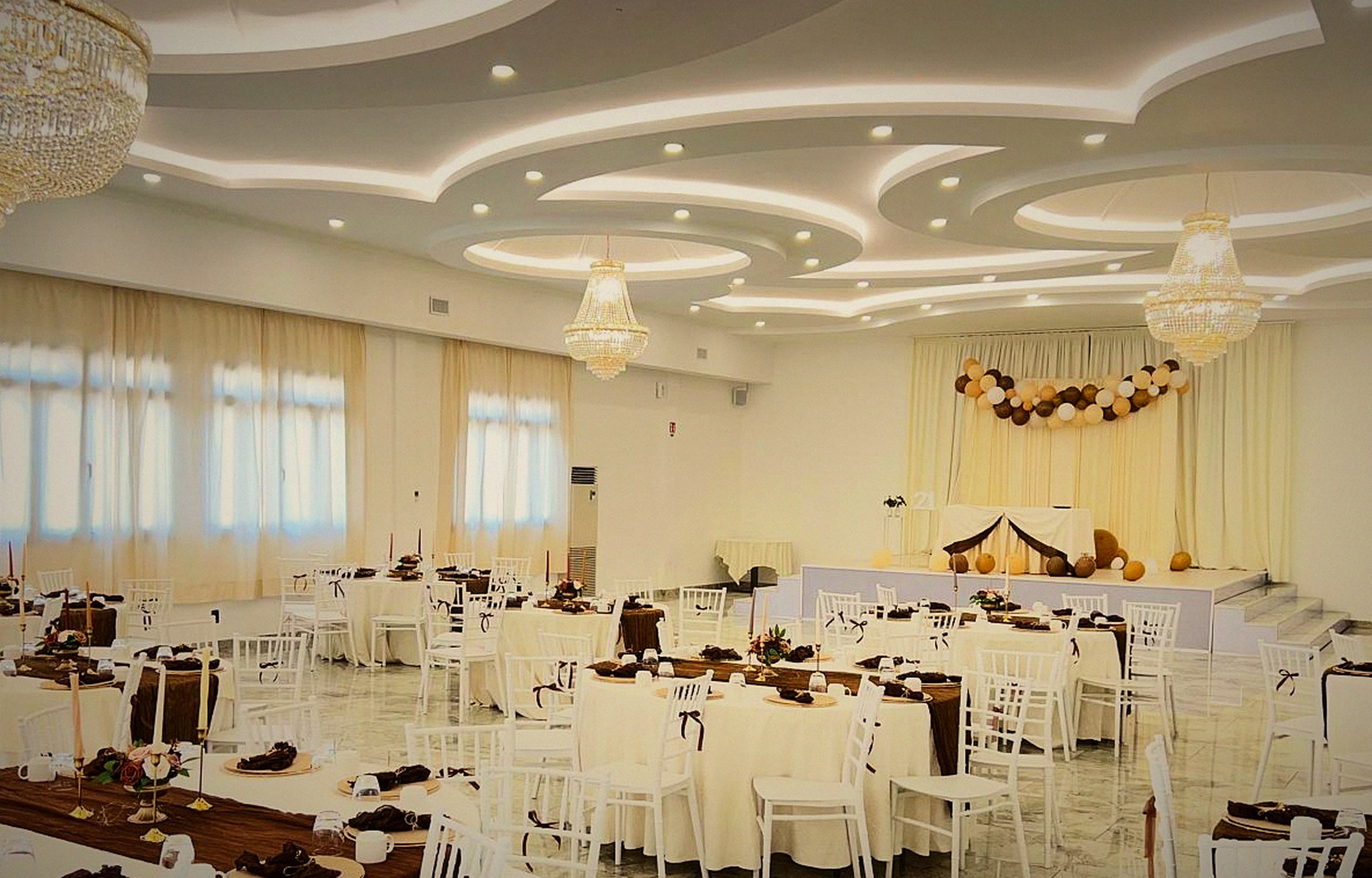La sala di JJ Resort sotto i lampadari di cristallo, allestita per un ricevimento